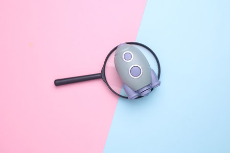 Space shuttle with magnifying glass on blue pink backgroundの写真素材