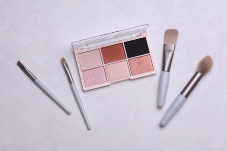 Makeup eyeshadow palette and brushes on concrete background