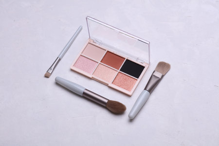 Makeup eyeshadow palette and brushes on concrete background