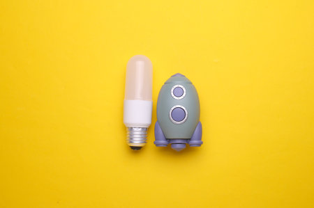 Toy space shuttle with light bulb on yellow background. Startup idea