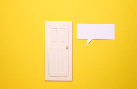 Miniature wooden door with speech bubble on yellow background