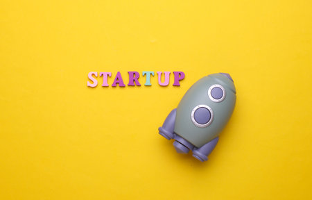 Toy space shuttle and word startup on yellow background.の写真素材