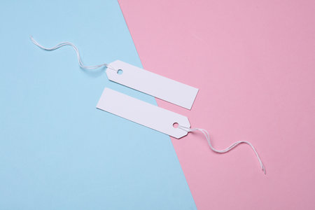 White paper tags on strings on a blue pink background