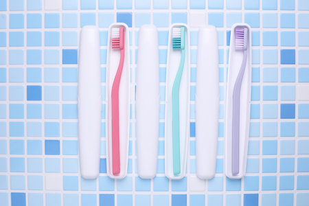 Plastic cases with toothbrushes on tile backgroundの写真素材