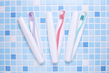 Plastic cases with toothbrushes on tile backgroundの写真素材