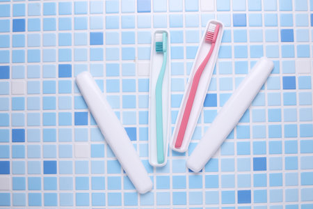 Plastic cases with toothbrushes on tile background