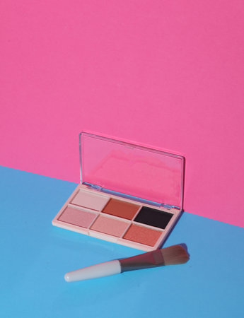 Makeup eyeshadow palette and brush on pink blue backgroundの写真素材