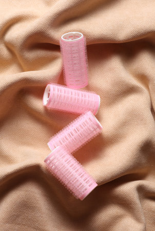 Pink hair curlers on beige velour backgroundの写真素材