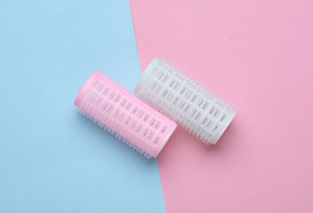 Plastic hair curlers on pink blue backgroundの写真素材