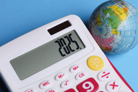 Calculator with number 2025 and globe on blue background. Economic analysis, budget of the yearの写真素材
