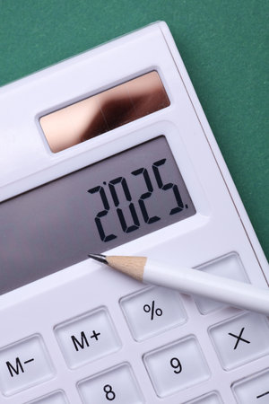 Calculator with number 2025 and pencil on green background. Economic analysis, budget of the yearの写真素材