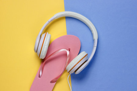 Flip flop with headphones on colored background. Summertime relax. Summer vacation. Beauty and fashion. Top view. Flat layの写真素材