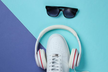 Sneakers with headphones and sunglasses on colored background. Urban modern design. Music concept. Flat lay, minimal.の写真素材