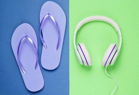 Flip flop and headphones on colored background. Summertime relax. Summer vacation. Beauty and fashion. Top view. Flat layの写真素材