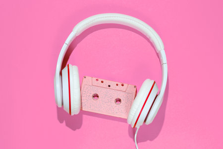 Audio cassette and headphones on pink background. Retro music concept. Vintage background. Disco...