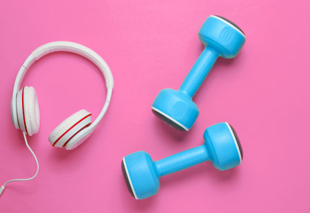 Sports equipment on pink background. Sport lifestyle. Dumbbells, headphones. Fitness concept. Top view, minimalism, flat layの写真素材