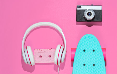 Hipster outfit. Skateboard with headphones, audio cassette on pink background. Creative fashion minimalism. Trendy retro 80s style. Minimal summer fun. Music concept. Top viewの写真素材
