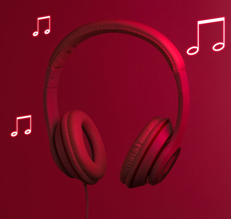 Stereo audio headphones with soaring notes in red neon light. Retro wave, 80sの写真素材
