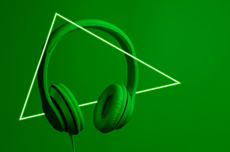 Retro wave. Headphones in green neon light with a luminous led triangle. 80sの写真素材