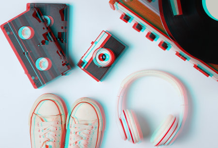 Flat lay retro 80s pop culture objects. Vinyl player, headphones, video tapes, film camera, sneakers on white background. Glitch effect. Top viewの写真素材