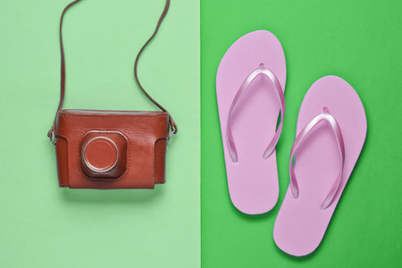 Flip flops and retro camera on green paper background. Trip, vacation concept. Summer fashion, holiday. Beach accessories.の写真素材