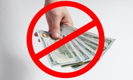 Stop the bribes. Hand holds hundred dollar bills, with a prohibition signの写真素材