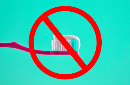 Toothpaste on a pink toothbrush close-up on a mint color light backgroundの写真素材