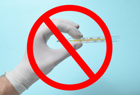 Medical man's hand with white latex gloves holds the thermometer on a blue background with prohibition sign. Medical conceptの写真素材