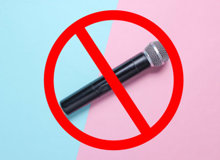 Wireless microphone on blue pink pastel background with prohibition sign. Flat lay. Top viewの写真素材