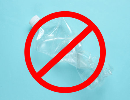 Stop plastic. Minimalistic ecological concept. Crumpled plastic bottle on blue background wth...