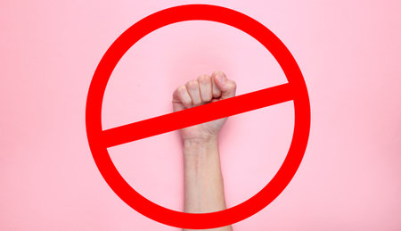 Feminism. Female fist on a pink background with prohibition sign. Top view, minimalismの写真素材