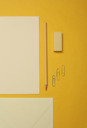 Creative layout of stationery, cards and sheets of paper on yellow background. Monochrome...