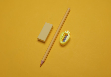 Pencil with eraser and sharpener on yellow background