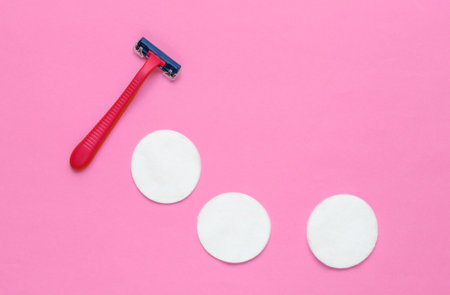 Beauty still life, minimalism. Plastic epilator razor with cotton circles on pink background....
