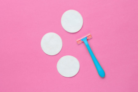Beauty still life, minimalism. Plastic epilator razor with cotton circles on pink background. Women's accessories for beauty care. Top viewの写真素材