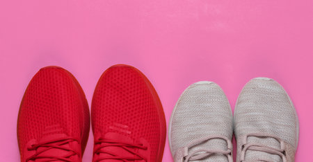 Two pairs of women's and men's sports shoes for running on pink background. Concept of couple doing sports.の写真素材