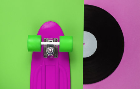 Retro style. Plastic mini cruiser board and vinyl record on colored background. Summer fun. Youth...