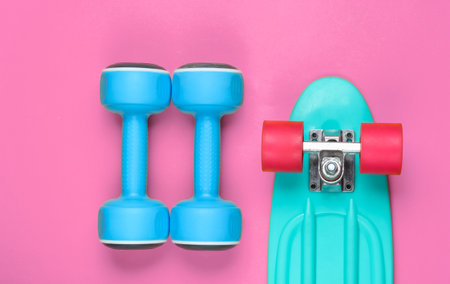 Cruiser board and dumbbell on pink background. Top viewの写真素材