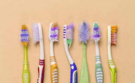 Old used toothbrushes on yellow background. Dental care concept. Top view