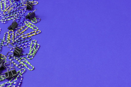 Lot of colored paper clips on purple background. Minimalistic office concept. Copy spaceの写真素材