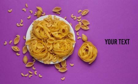Different types of raw italian pasta in plate on purple background. Top view. Copy spaceの写真素材
