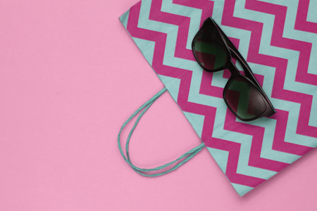 Minimalism shopping concept. Paper shopping bag and sunglasses on pink background. Top viewの写真素材