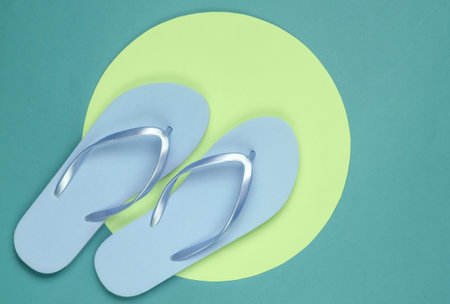 Flip flops on green background with yellow circle. Minimalistic vacation on the beach concept. Summer timeの写真素材