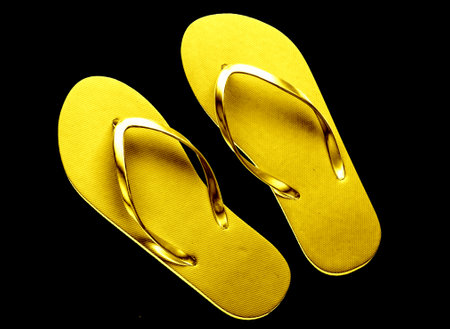 Golden flip flops isolated on black background.の写真素材