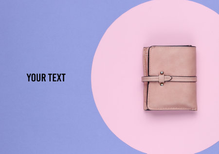 Stylish women's leather wallet on a purple background with a pink pastel circle. Creative minimalistic fashion still life. Copy spaceの写真素材