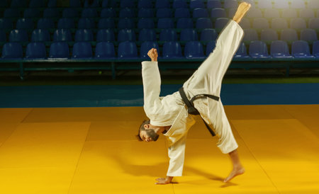 Sport man in white kimono practices capoeira in the sports hallの写真素材