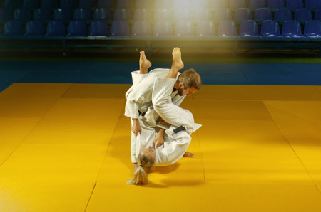 Martial arts. Sparing Portners. Sport man and woman in white kimono train judo throws and captures...