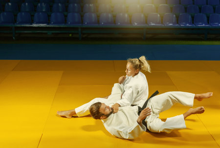 Martial arts. Sparing Portners. Sport man and woman in white kimono train judo throws and captures...