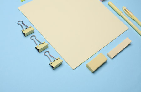 Paper sheets and yellow Stationery set on blue background. Back to school, education, office...