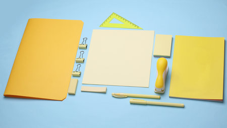 Paper sheets and yellow Stationery set on blue background. Back to school, education, office...